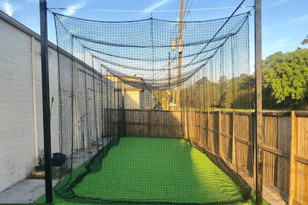 The netting and frame of a backyard batting cage seen down the tunnel
