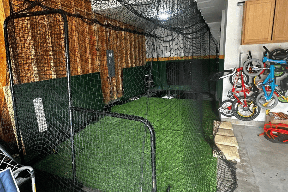 Garage batting cage with turf, padding, and an L-screen