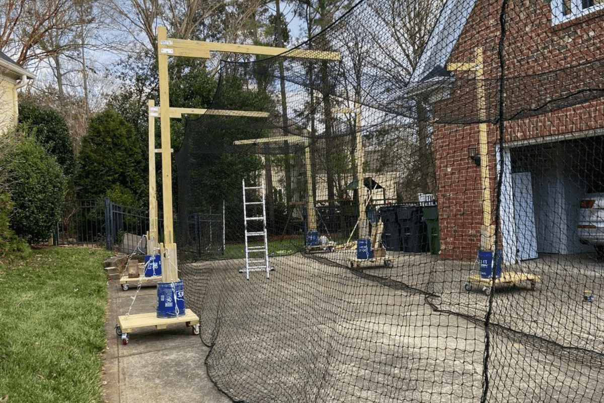 A batting cage frame under construction in a backyard