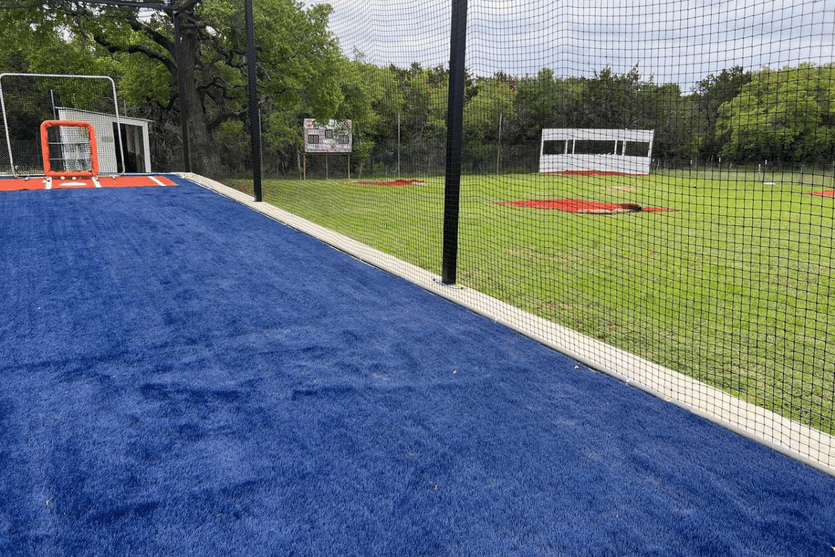 A backyard batting cage with synthetic turf laid down the lane