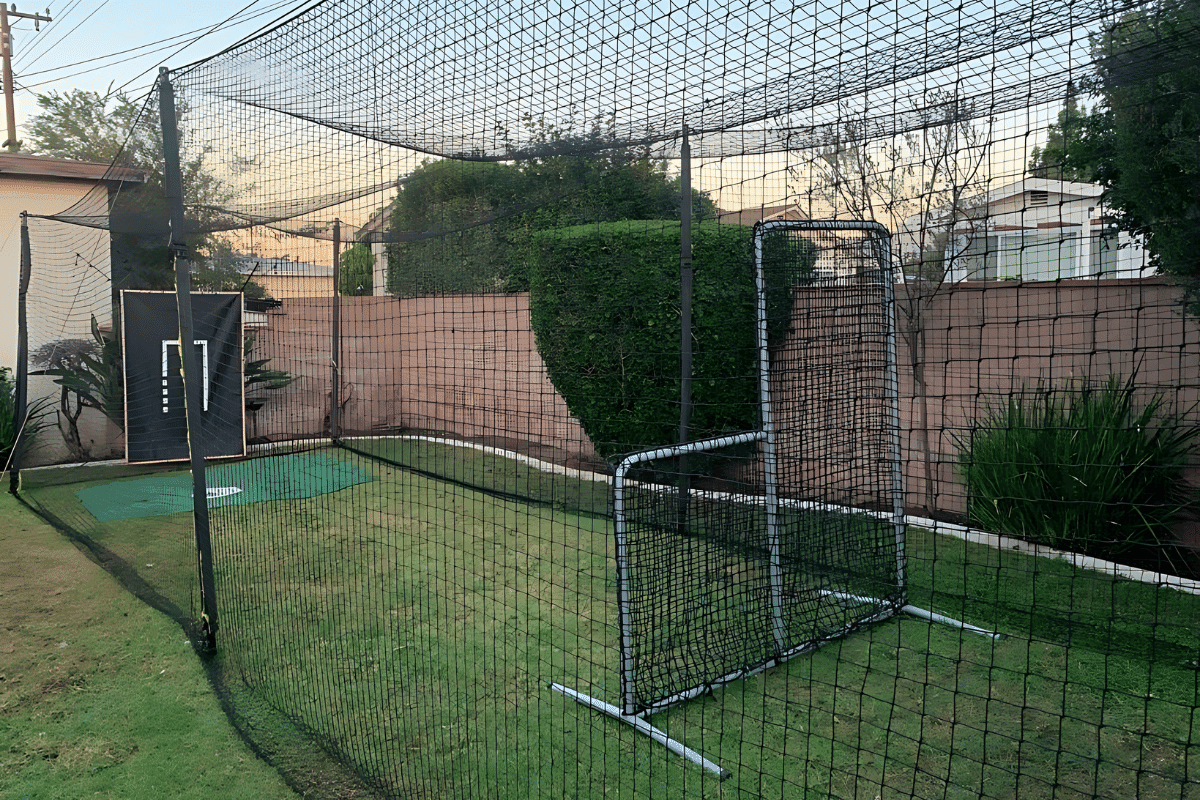 An L-screen set up to protect the feeder in a backyard batting cage