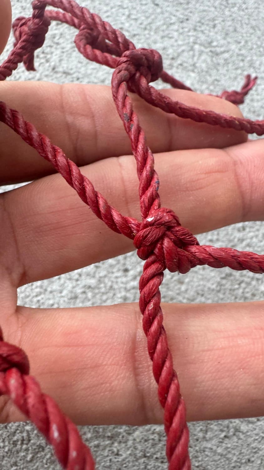 Close-up of a thick knotted #60 net twine held across a hand