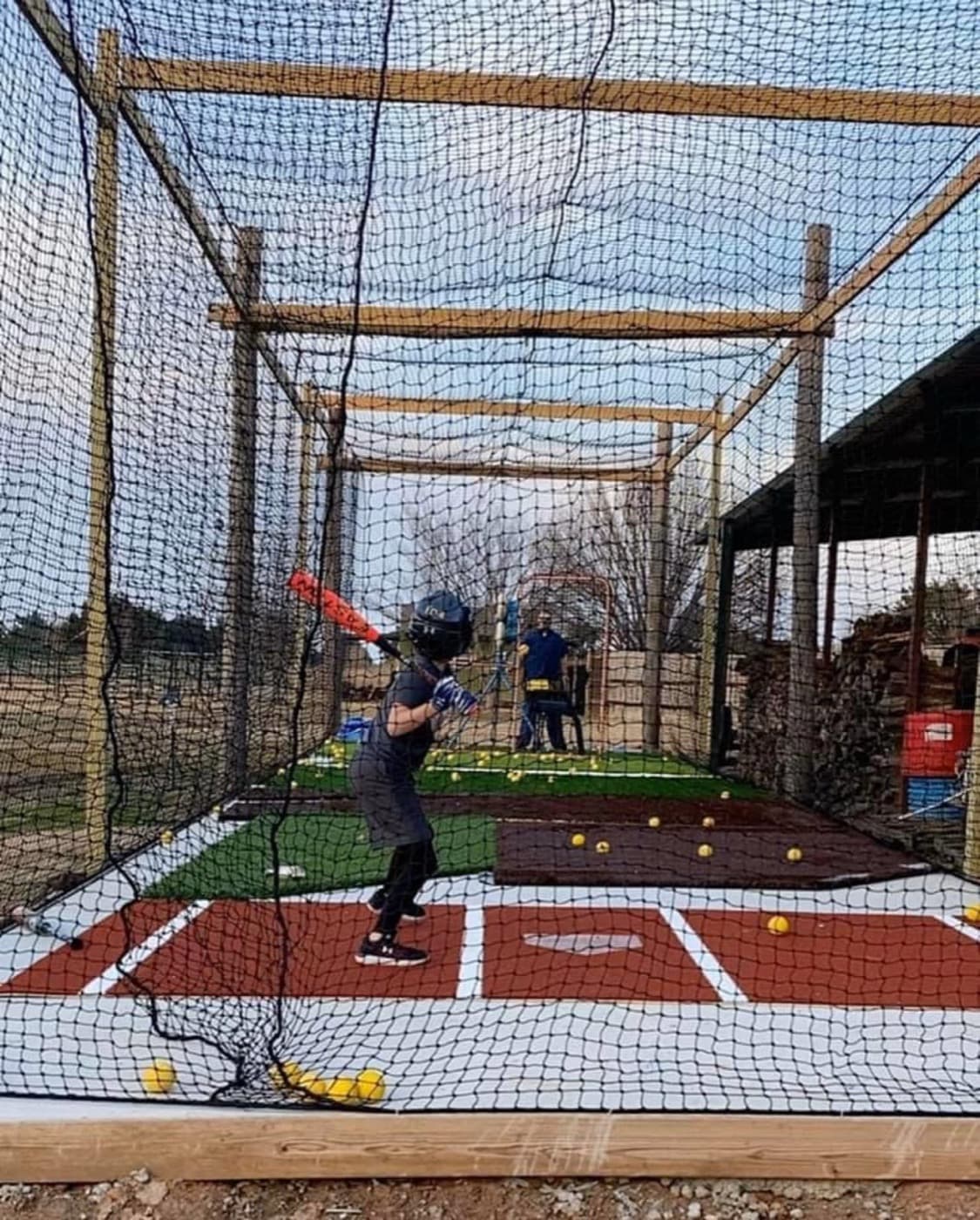 A young hitter taking a swing in a turf batting cage