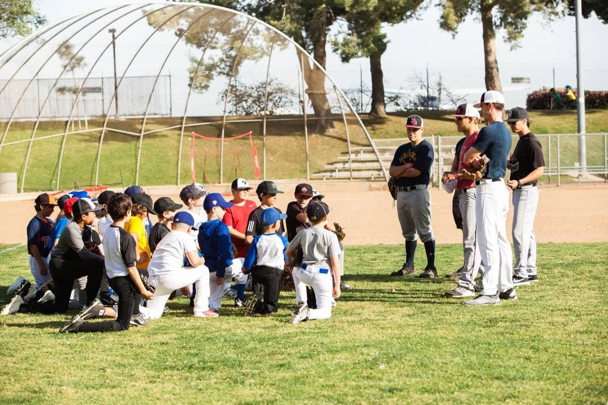 Coaches standing in front of a group of players kneeling on the grass