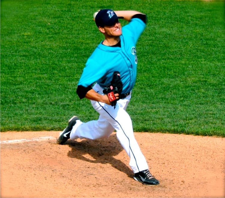 Isaac Hess pitching in a teal jersey, mid-delivery