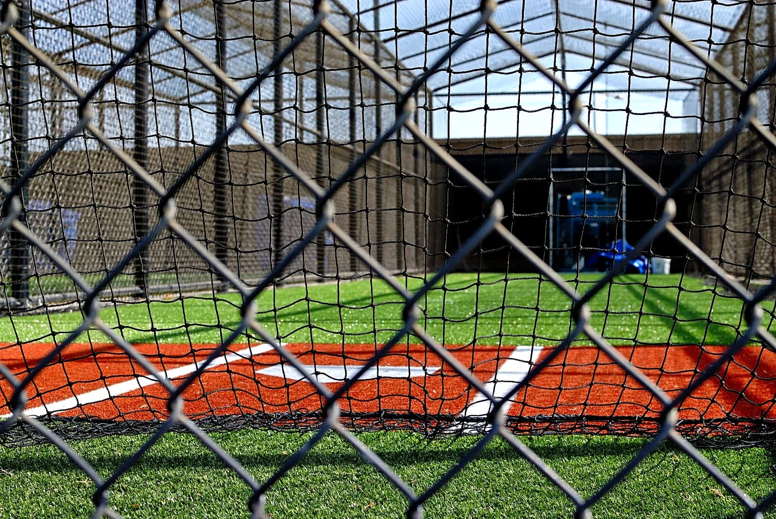 A player at bat in a backyard batting cage at dusk