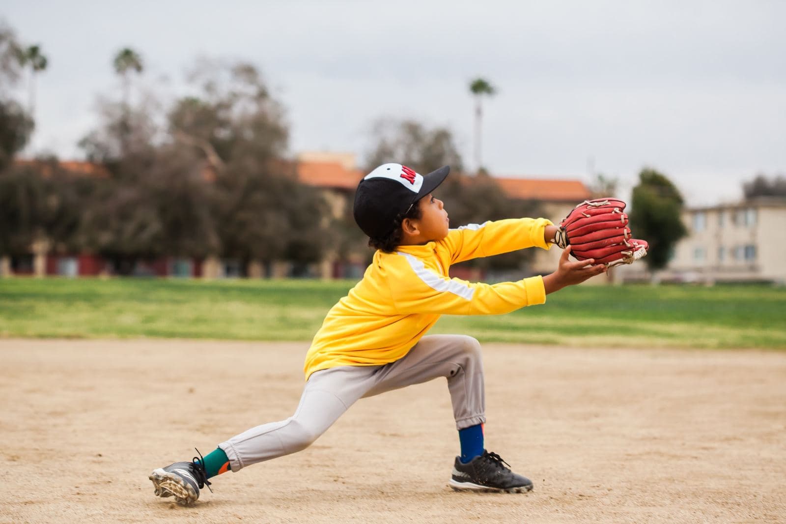 A young player stretching low to catch a throw with his glove