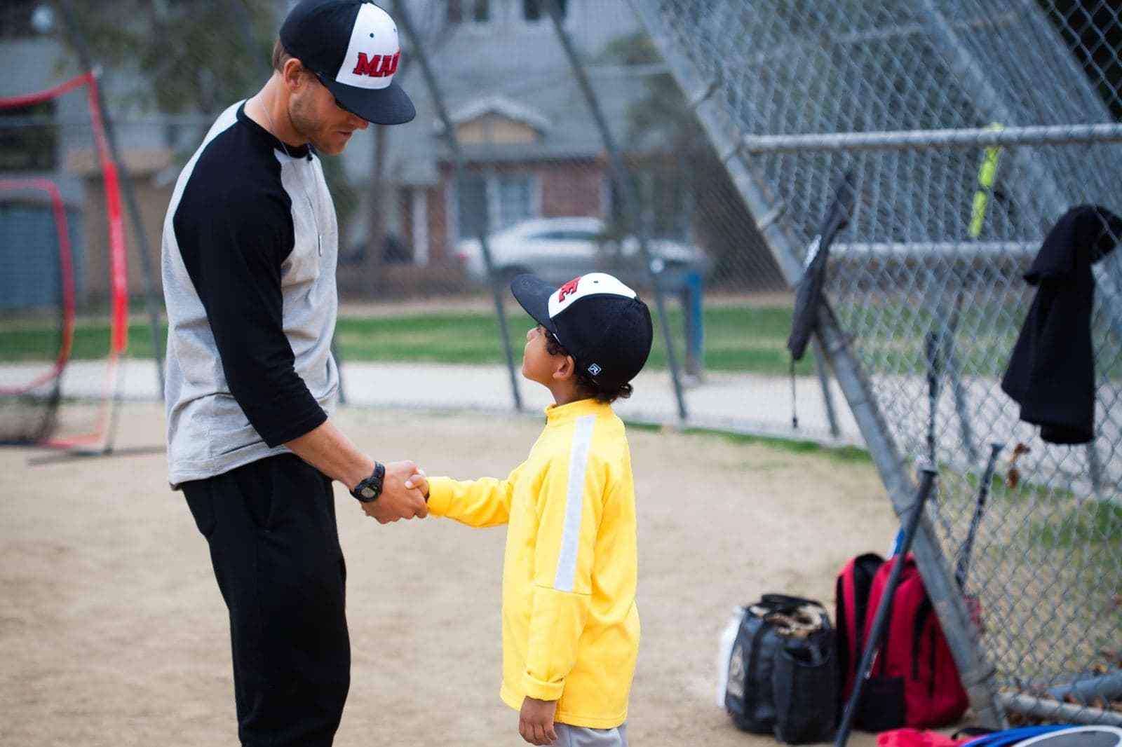 Coach Isaac Hess shaking hands with a young player in a yellow pullover