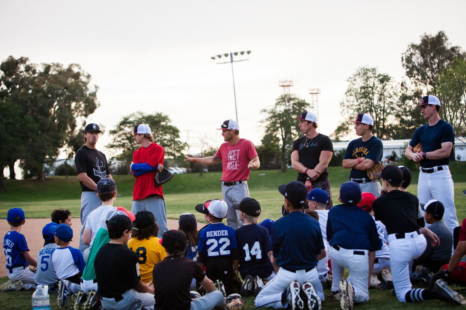 Coach Isaac Hess in a #GETMADE shirt talking to a camp of young players taking a knee