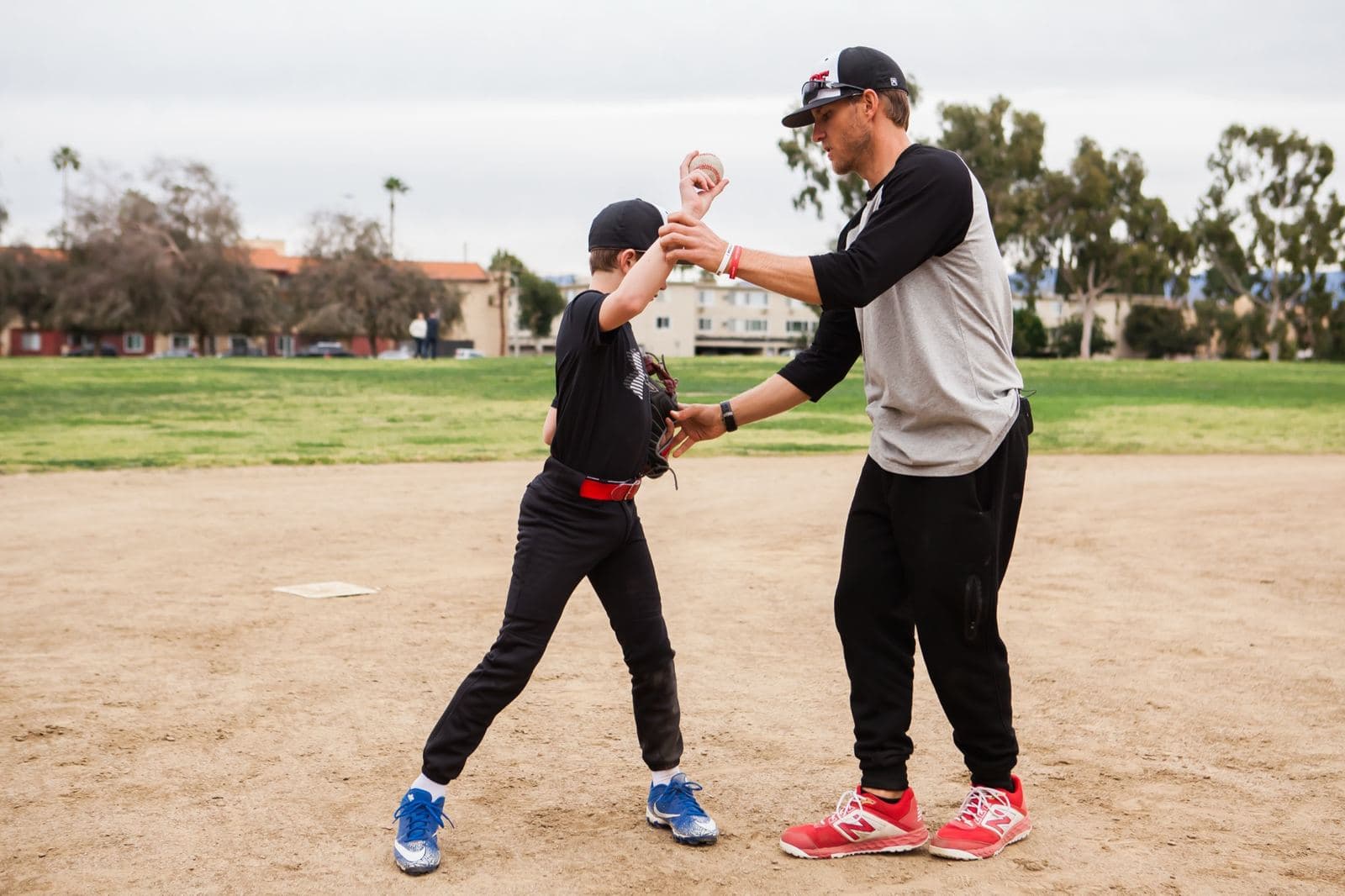 Coach Isaac Hess guiding a young player's throwing arm during a one-on-one lesson
