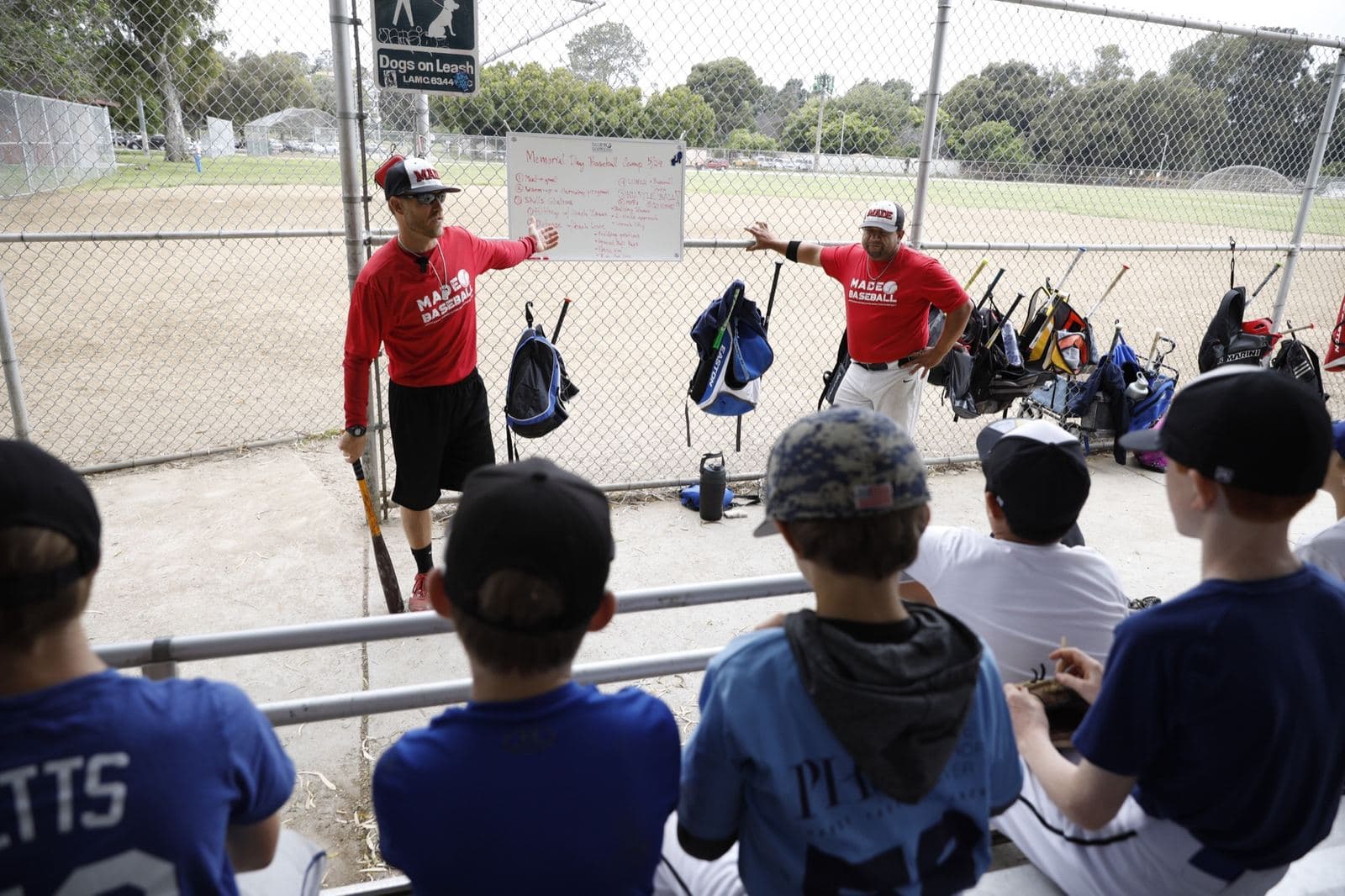 Two coaches at a whiteboard explaining a play to a group of seated players