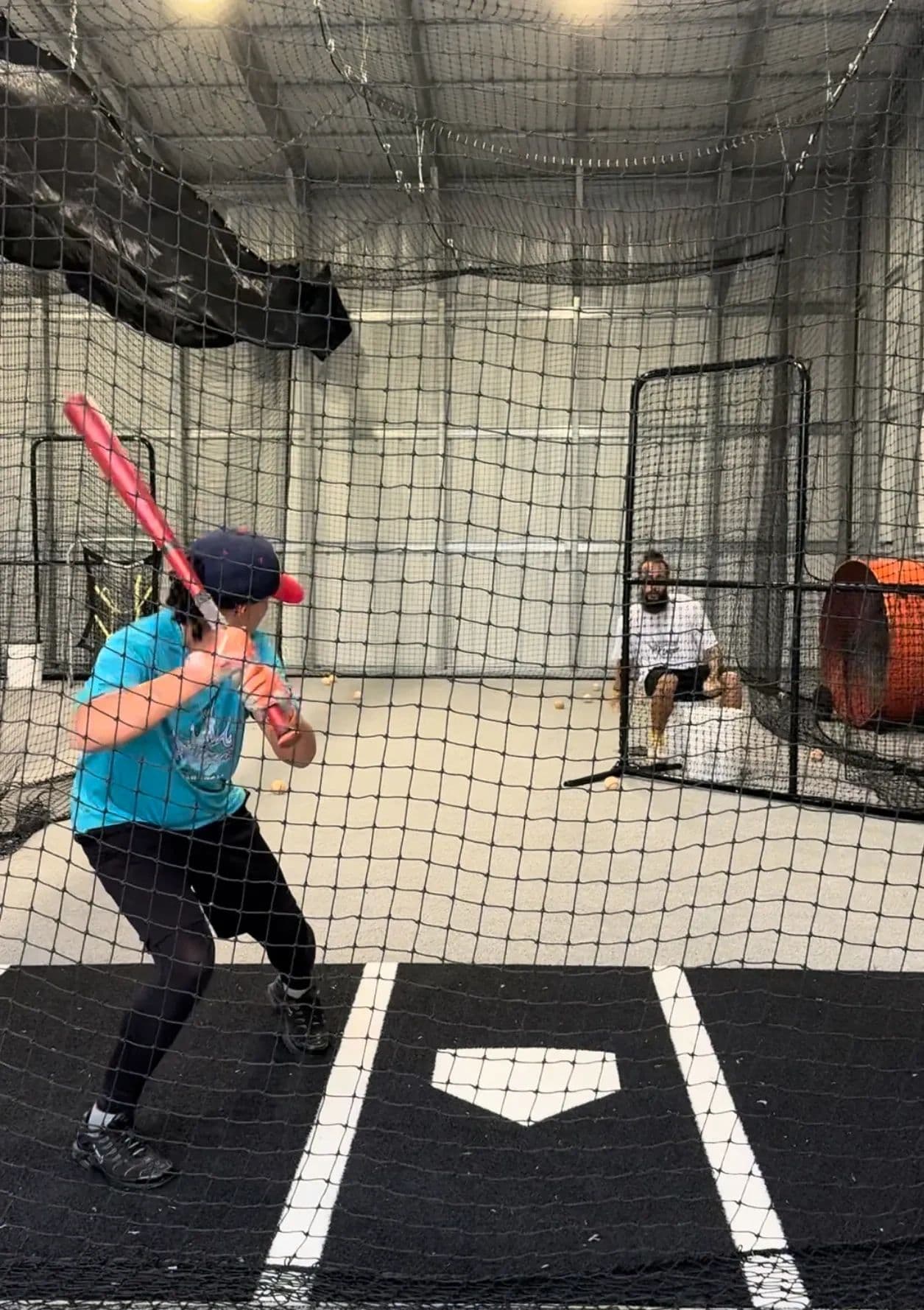 A hitter taking front toss behind an L-screen at Swing Kingz