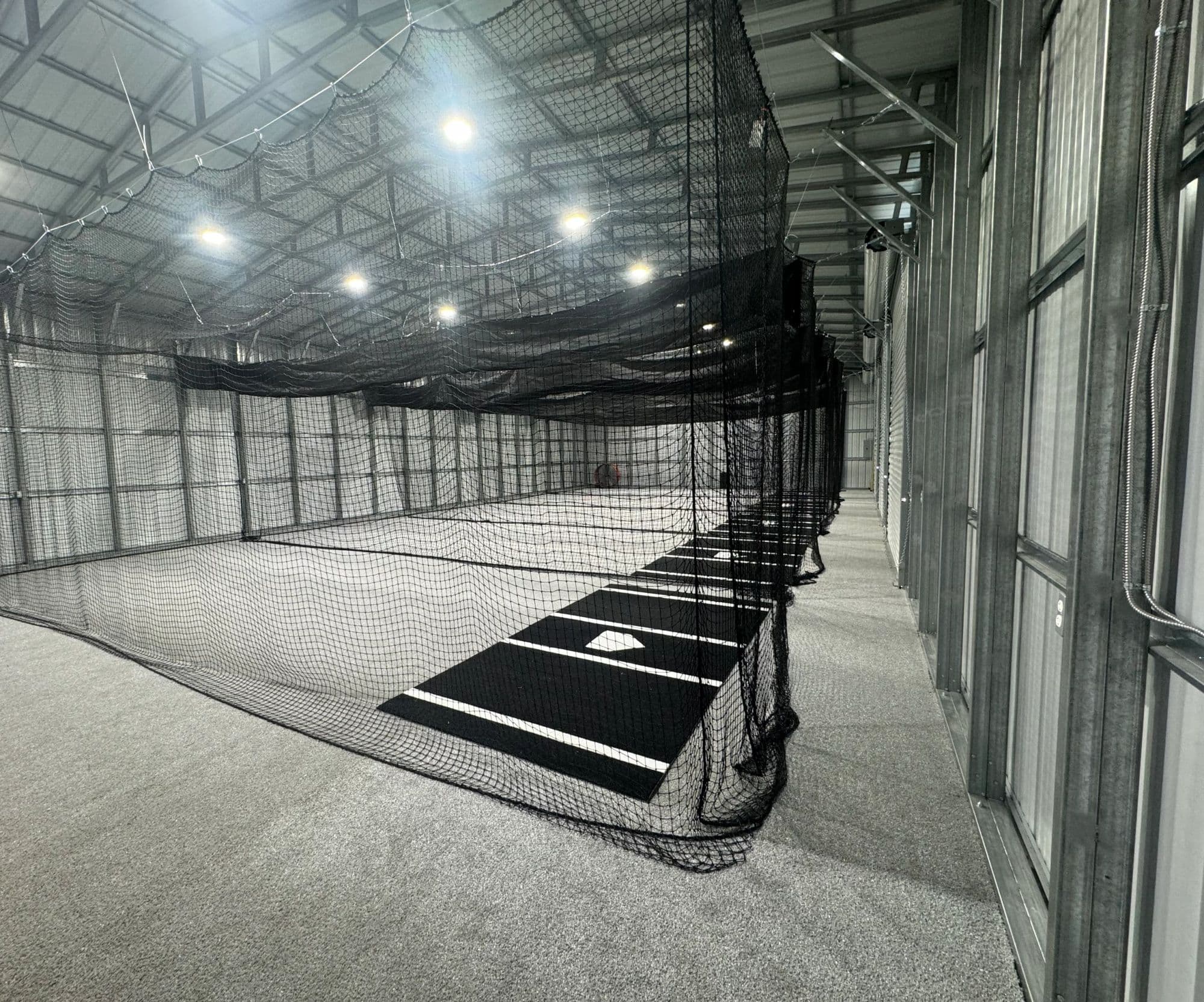 Wide view down the turf at Swing Kingz, netting and home plate in frame