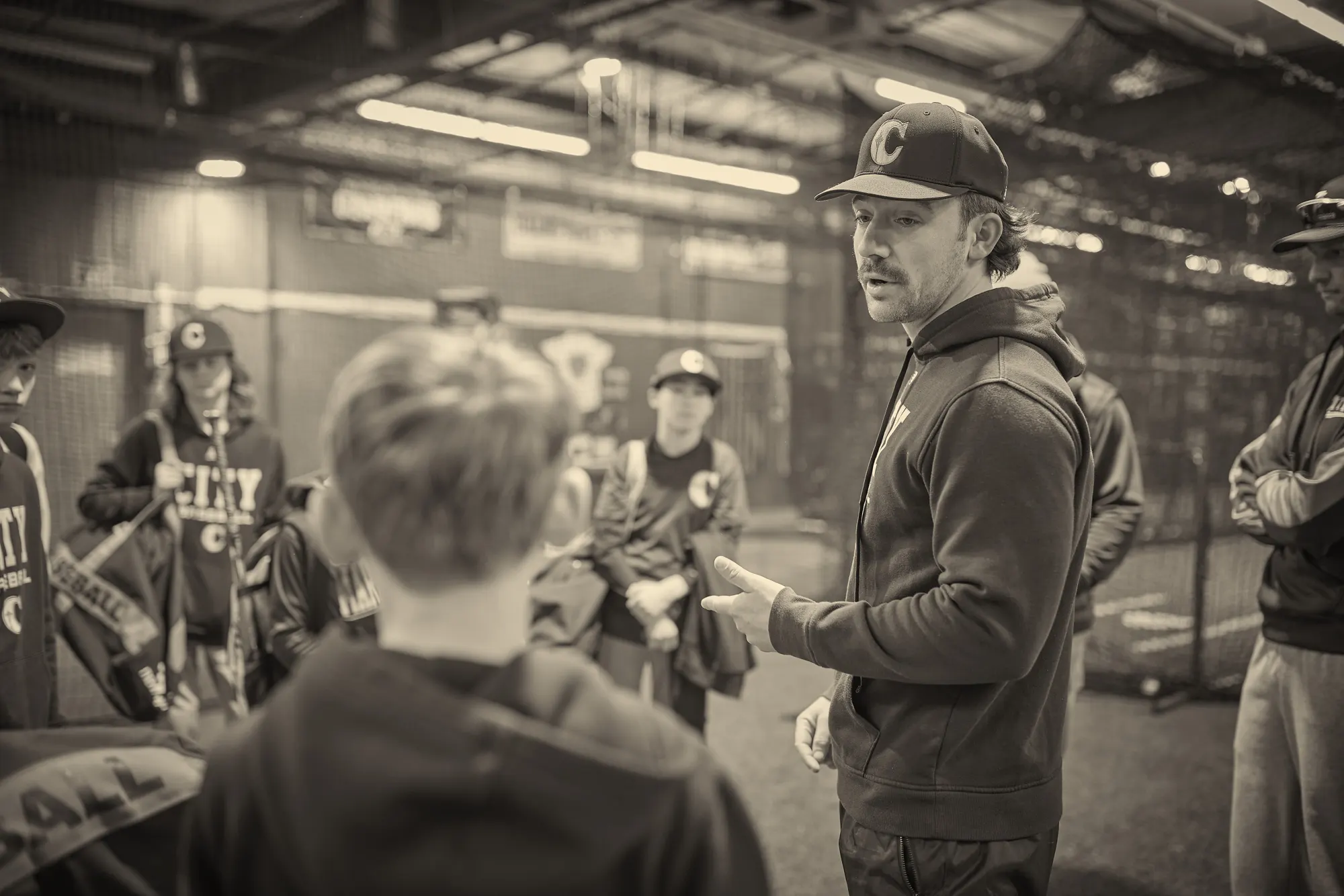 A coach talks with a group of City Baseball players inside the Seattle Baseball Academy facility