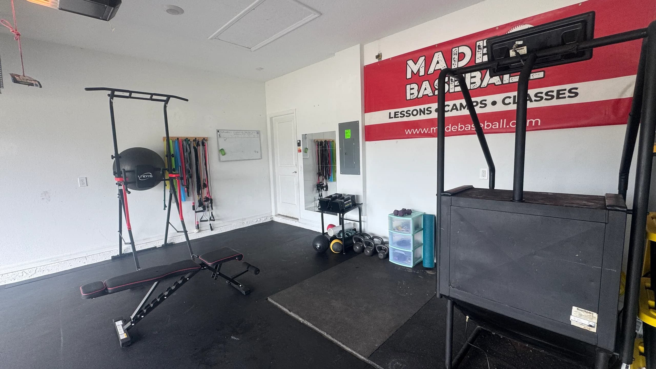 Interior of the MADE Baseball garage facility with matted flooring and training equipment