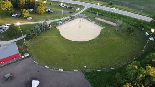 A baseball resting on the pitching rubber of a lit turf field at night