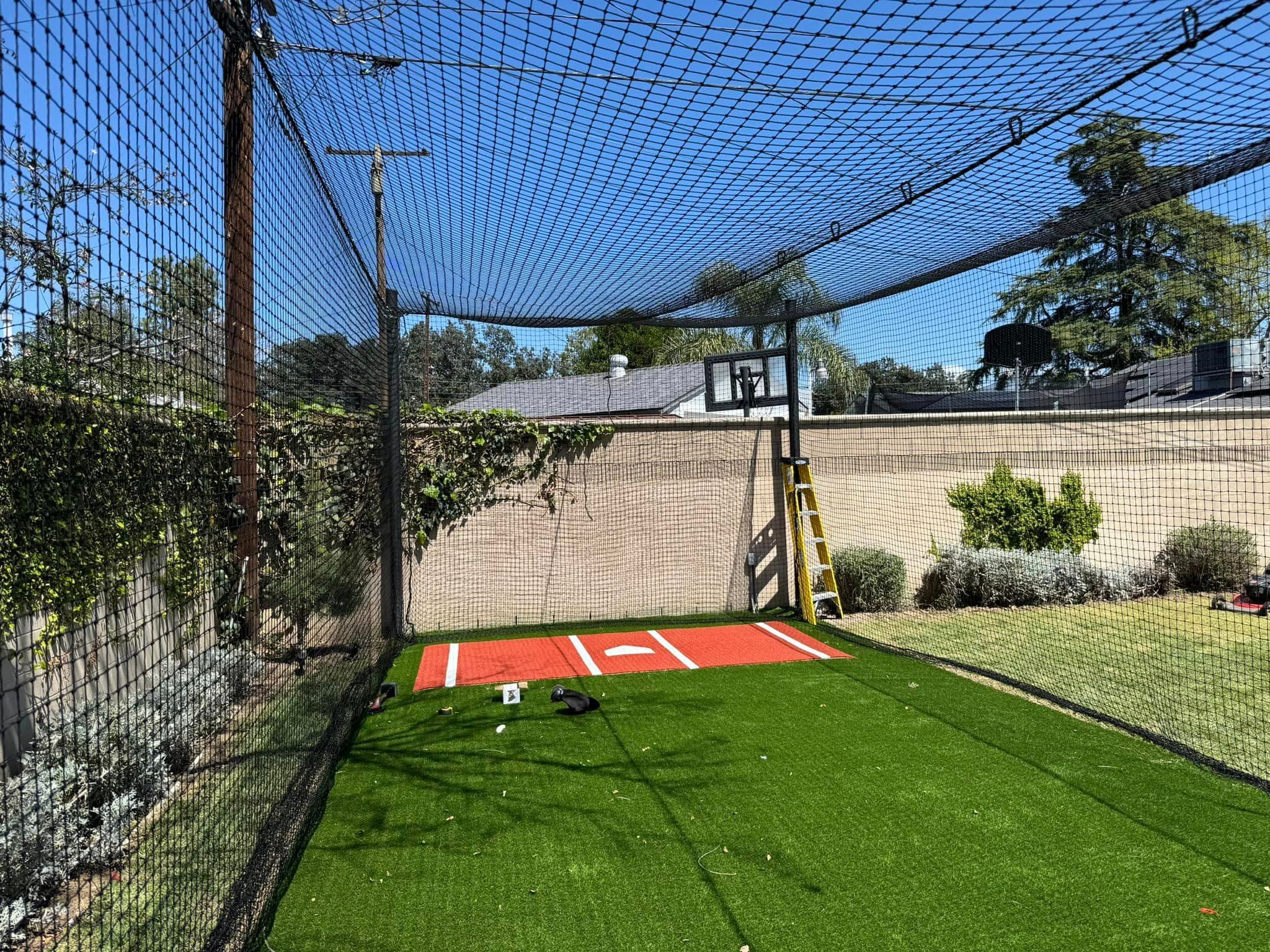 Backyard batting cage with turf batter box and netting