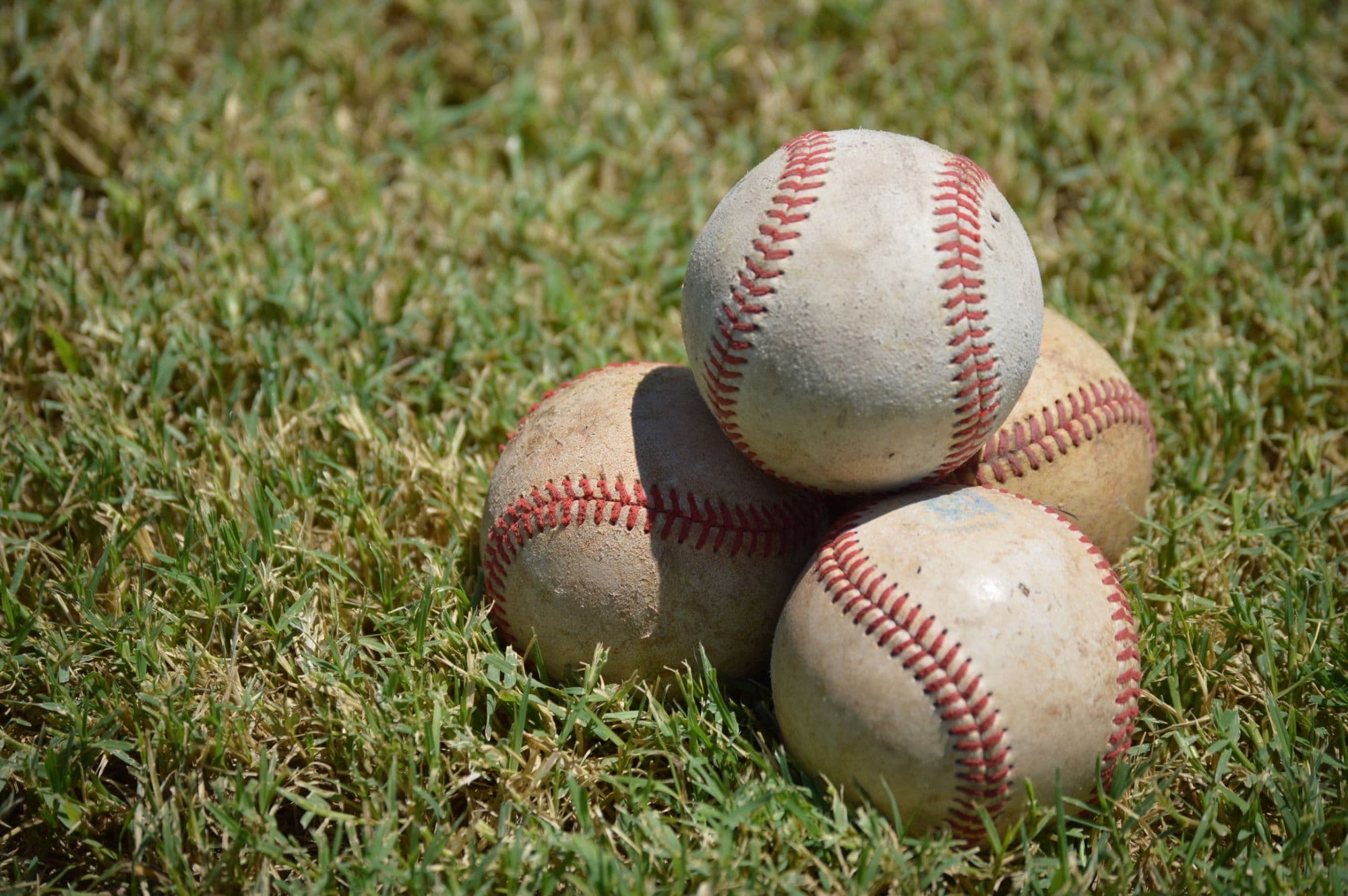 Stack of used baseballs on a grass field